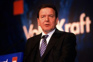 Mann im dunklen Anzug spricht am Rednerpult vor unscharfem Hintergrund mit Text.