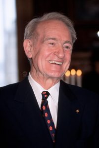 Älterer Mann in Anzug und Krawatte, der lächelnd nach rechts schaut.