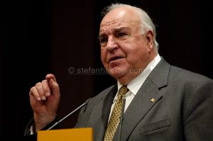 Älterer Mann im Anzug spricht gestikulierend an einem Mikrofon.